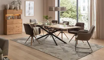 Zweigeteiltes Wohnbild: links sitzt eine Frau entspannt lesend in einem hellen Lounge-Sessel; rechts ein stilvoll eingerichtetes Wohnzimmer mit Naturtönen, runder Polstergarnitur, Dekovasen und Holzdetails, dazu das Natura Home Logo.